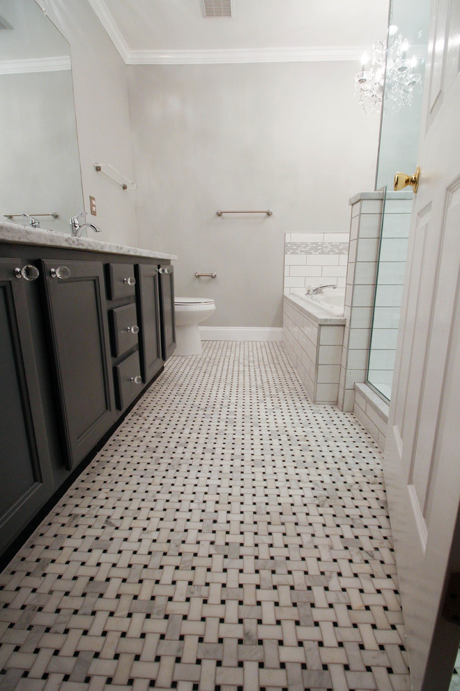 ニューヨークにあるお手頃価格の中くらいなトラディショナルスタイルのおしゃれなマスターバスルーム (フラットパネル扉のキャビネット、グレーのキャビネット、ドロップイン型浴槽、コーナー設置型シャワー、小便器、白いタイル、セラミックタイル、グレーの壁、モザイクタイル、アンダーカウンター洗面器、大理石の洗面台、白い床、開き戸のシャワー) の写真