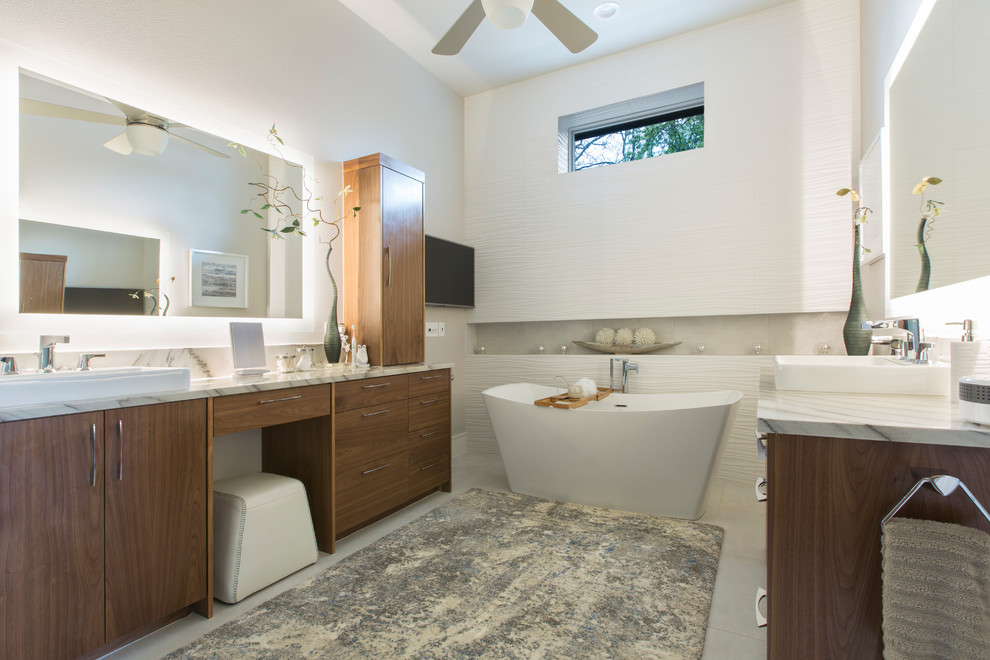 Réalisation d'une salle de bain principale design en bois brun avec un placard à porte plane, une baignoire indépendante, un carrelage blanc, un mur blanc, une vasque, un sol blanc et un plan de toilette blanc.