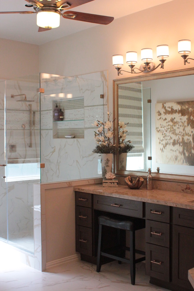 Example of a large marble floor bathroom design in Dallas with a drop-in sink, glass-front cabinets, brown cabinets, granite countertops, a one-piece toilet and beige walls