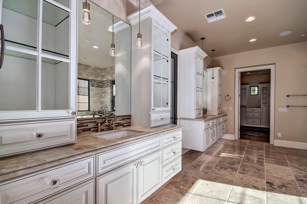 Bathroom - large mediterranean master gray tile and stone tile limestone floor and beige floor bathroom idea in Phoenix with raised-panel cabinets, white cabinets, a two-piece toilet, a drop-in sink, quartzite countertops, beige walls and a hinged shower door