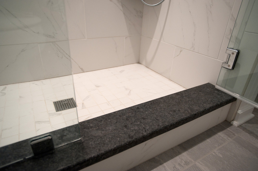 Medium sized traditional ensuite bathroom in Philadelphia with white cabinets, an alcove shower, a two-piece toilet, white tiles, ceramic tiles, blue walls, cement flooring, a submerged sink, grey floors, a hinged door, shaker cabinets, solid surface worktops and black worktops.
