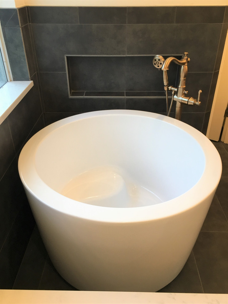 Photo of a medium sized contemporary ensuite bathroom in Austin with recessed-panel cabinets, medium wood cabinets, a japanese bath, a corner shower, a two-piece toilet, white tiles, ceramic tiles, white walls, porcelain flooring, a submerged sink, engineered stone worktops, black floors, a hinged door and white worktops.