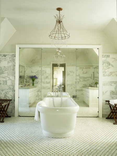 Klassisk inredning av ett stort en-suite badrum, med vita skåp, ett fristående badkar, en dusch i en alkov, en toalettstol med hel cisternkåpa, vit kakel, marmorkakel, beige väggar, marmorgolv, ett undermonterad handfat, bänkskiva i kalksten, vitt golv, dusch med gångjärnsdörr och luckor med profilerade fronter