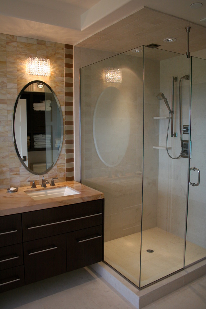 Inredning av ett maritimt stort en-suite badrum, med ett undermonterad handfat, släta luckor, svarta skåp, marmorbänkskiva, ett undermonterat badkar, en hörndusch, beige kakel, stenkakel, flerfärgade väggar och kalkstensgolv