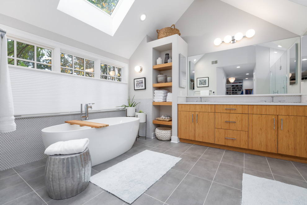 Idée de décoration pour une salle de bain design en bois brun de taille moyenne avec un placard à porte plane, une baignoire indépendante, un carrelage blanc, mosaïque, un mur gris, un lavabo encastré, un sol gris et un plan de toilette blanc.