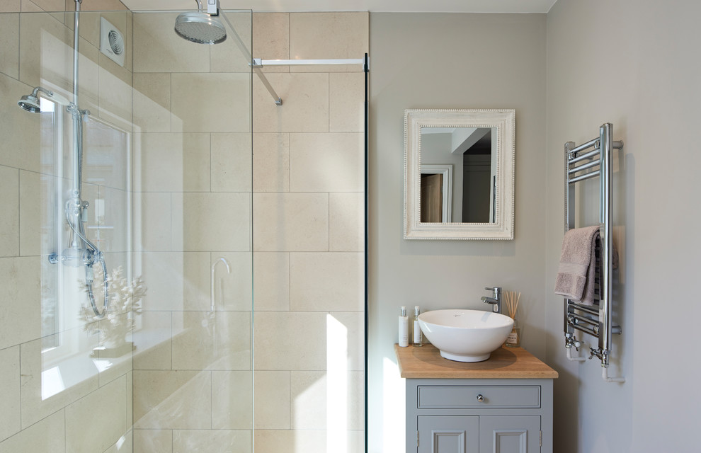 Photo of a traditional shower room bathroom in Hertfordshire with recessed-panel cabinets, grey cabinets, a corner shower, beige tiles, grey walls, a vessel sink, wooden worktops and brown worktops.