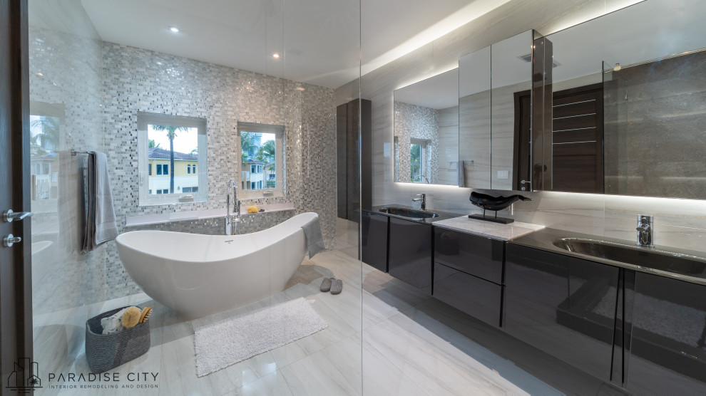 Design ideas for a large contemporary ensuite bathroom in Miami with flat-panel cabinets, grey cabinets, a freestanding bath, a corner shower, a bidet, white tiles, porcelain tiles, white walls, porcelain flooring, an integrated sink, glass worktops, white floors, a sliding door, black worktops, a wall niche, double sinks and a floating vanity unit.