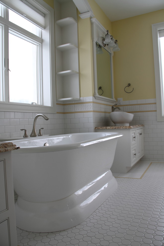 Klassisk inredning av ett stort en-suite badrum, med luckor med infälld panel, vita skåp, ett fristående badkar, en hörndusch, en toalettstol med hel cisternkåpa, vit kakel, keramikplattor, gula väggar, klinkergolv i keramik, ett fristående handfat och granitbänkskiva