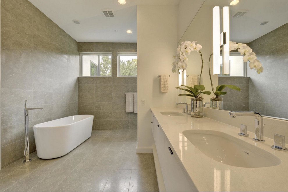 Foto di una stanza da bagno padronale minimal di medie dimensioni con lavabo sottopiano, ante lisce, ante bianche, vasca freestanding e piastrelle in pietra