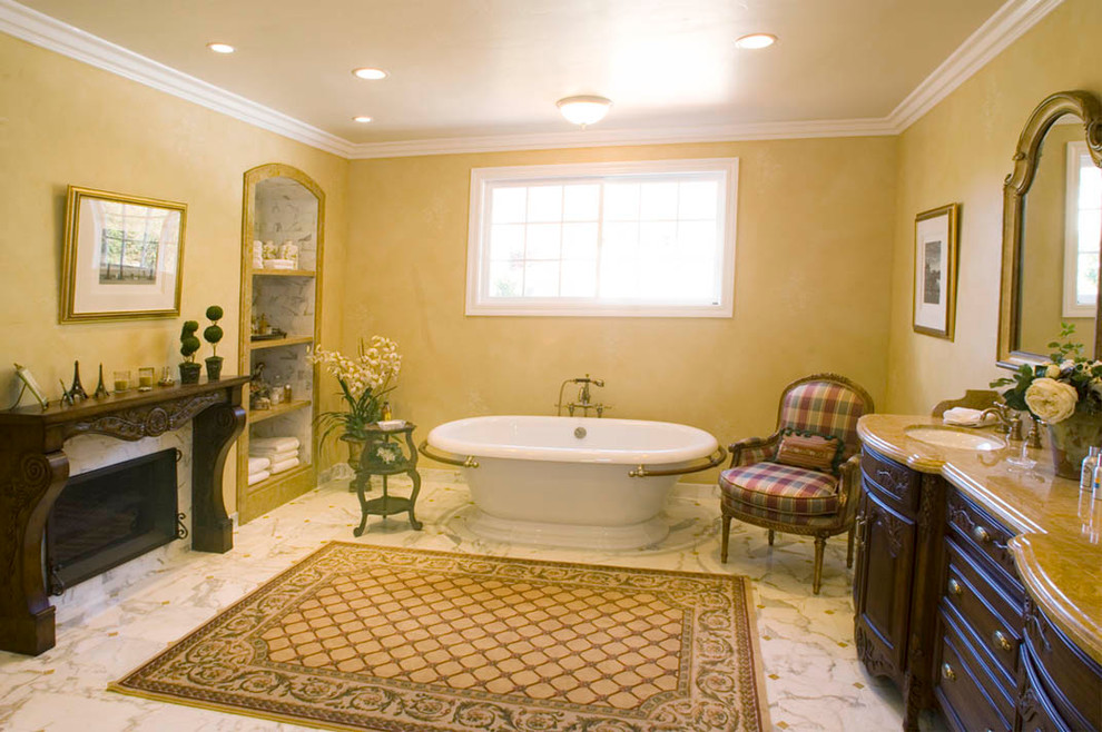 Foto de cuarto de baño principal tradicional con lavabo bajoencimera, armarios tipo mueble, puertas de armario de madera oscura, encimera de mármol, bañera exenta, ducha esquinera y suelo de mármol