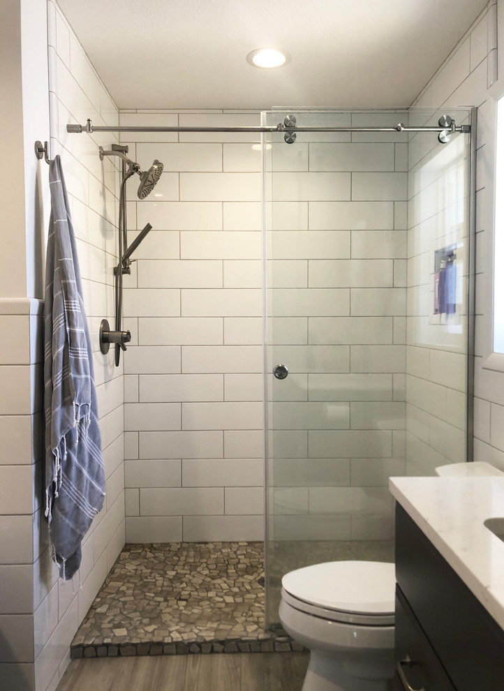 Design ideas for a medium sized classic ensuite bathroom in Seattle with shaker cabinets, grey cabinets, a freestanding bath, a walk-in shower, a two-piece toilet, white tiles, metro tiles, white walls, ceramic flooring, a built-in sink, engineered stone worktops, grey floors, a shower curtain and white worktops.