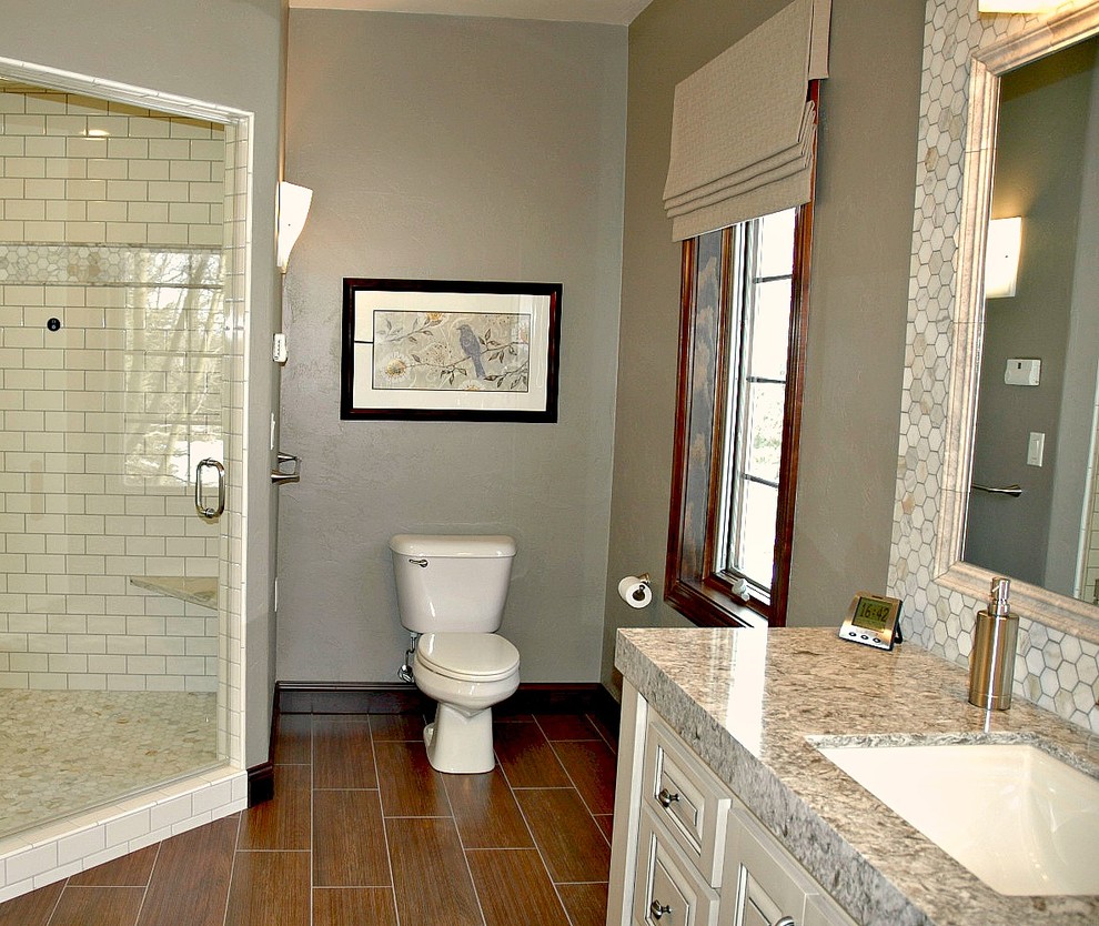 Transitional master brown tile and wood-look tile ceramic tile corner shower photo in Other with an undermount sink, raised-panel cabinets, white cabinets, quartz countertops, a two-piece toilet and gray walls