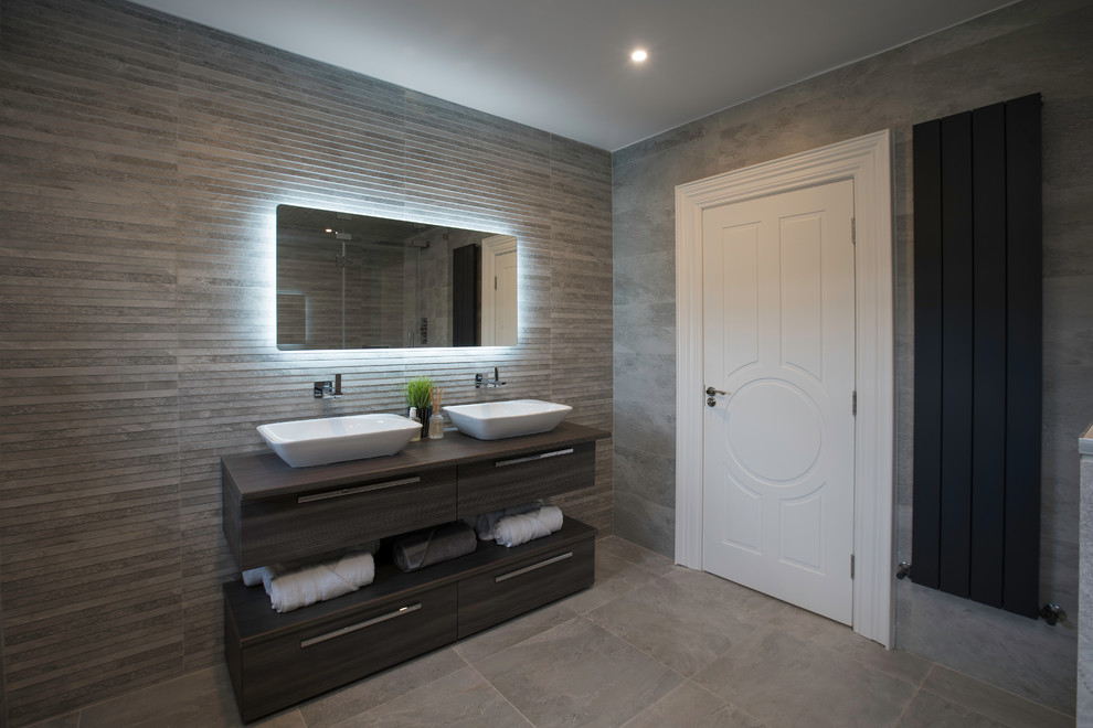 Design ideas for a large contemporary ensuite bathroom in Dublin with a built-in shower, a one-piece toilet, grey tiles, grey walls, a wall-mounted sink, grey floors, a hinged door and grey worktops.