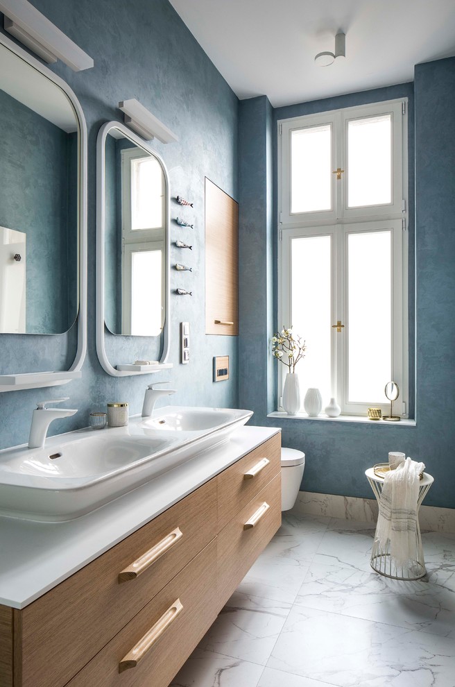 Example of a 1950s white floor bathroom design in Other with flat-panel cabinets, a wall-mount toilet, blue walls, a vessel sink and white countertops