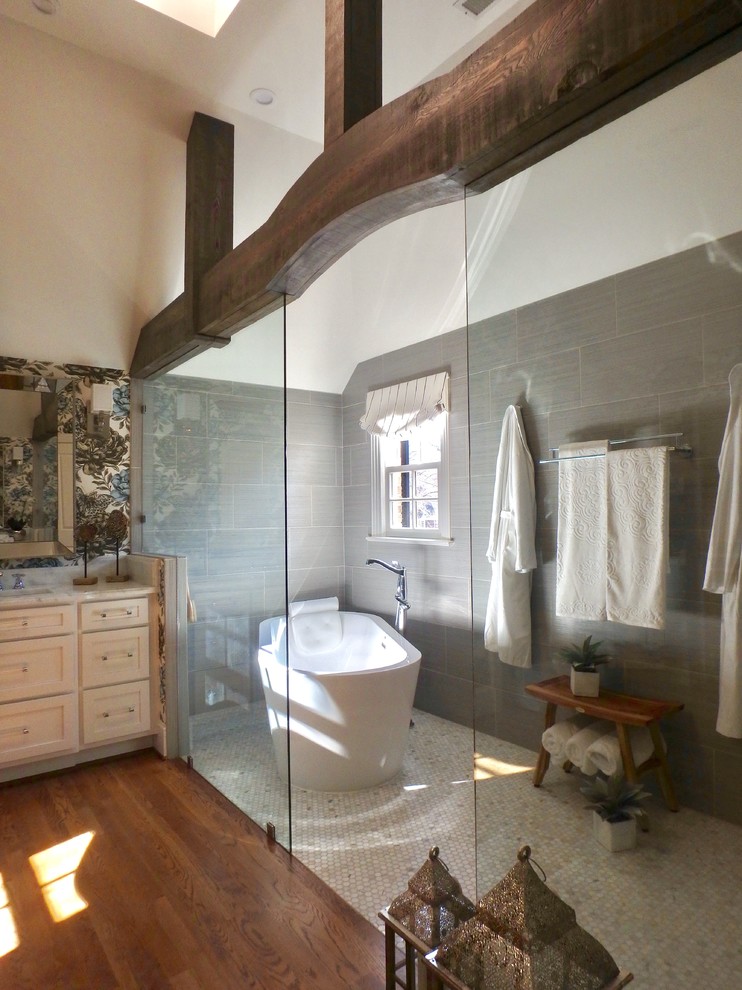 Inredning av ett modernt mellanstort en-suite badrum, med skåp i shakerstil, vita skåp, ett fristående badkar, en toalettstol med hel cisternkåpa, grå kakel, mosaik, vita väggar, ett undermonterad handfat, marmorbänkskiva, våtrum, mellanmörkt trägolv och brunt golv