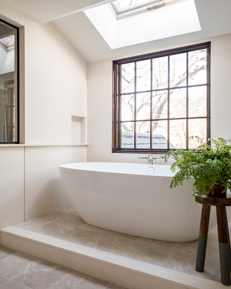 Klassisk inredning av ett vit vitt en-suite badrum, med ett fristående badkar, våtrum, en vägghängd toalettstol, dusch med gångjärnsdörr, skåp i mellenmörkt trä, ett undermonterad handfat, luckor med profilerade fronter, beige kakel och stenhäll