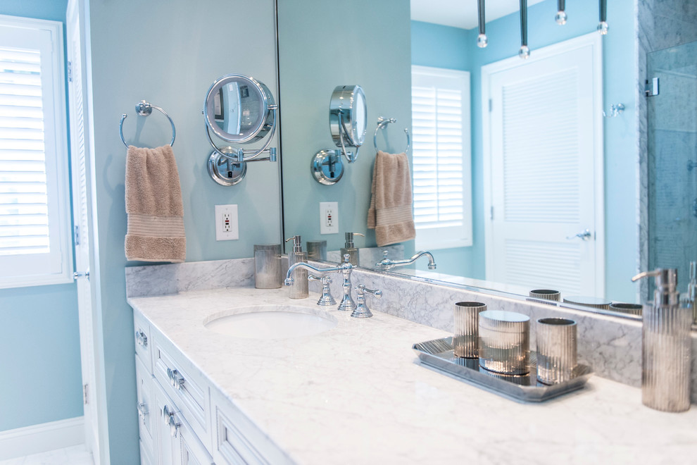 Idée de décoration pour une salle de bain principale marine de taille moyenne avec un lavabo encastré, un placard avec porte à panneau surélevé, des portes de placard blanches, un plan de toilette en onyx, un carrelage blanc, un carrelage de pierre, un mur bleu et un sol en marbre.