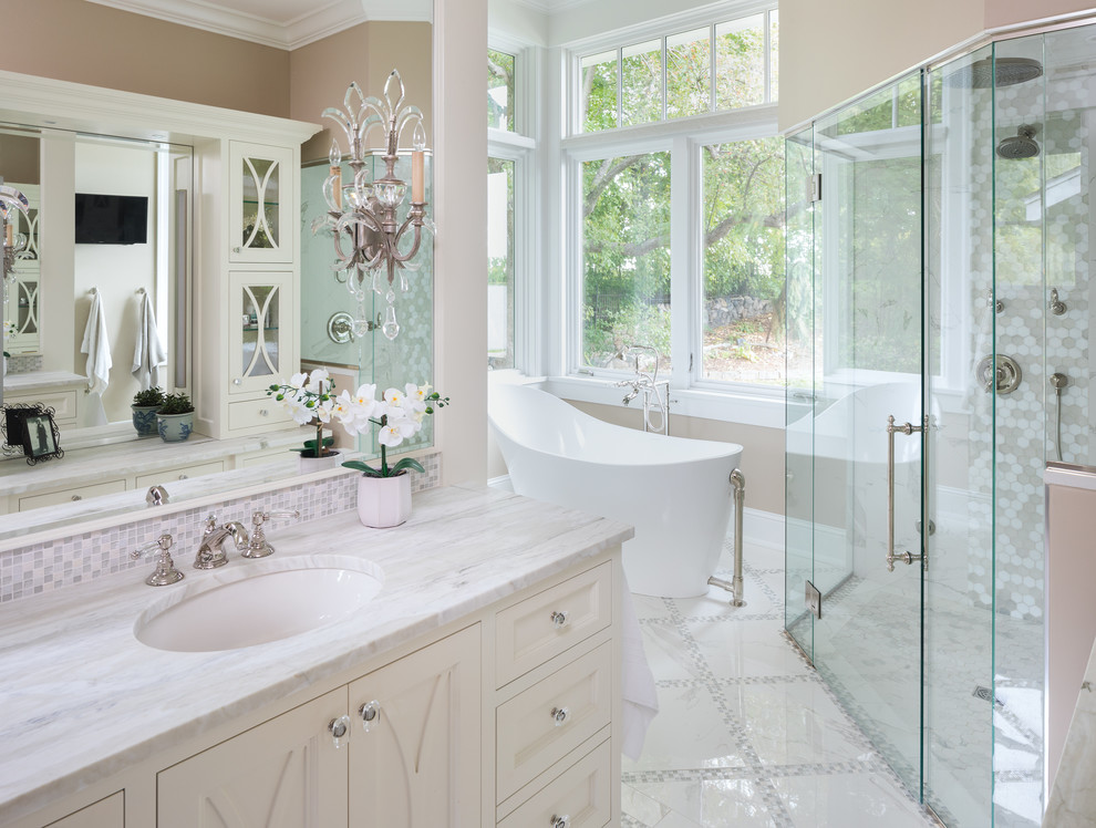 Esempio di una stanza da bagno classica con ante con riquadro incassato, ante beige, vasca freestanding, piastrelle beige, pareti beige, lavabo sottopiano, pavimento bianco e top bianco