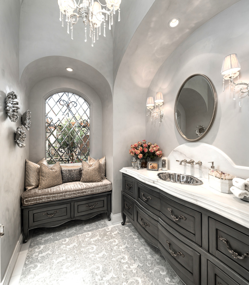 Пример оригинального дизайна: огромная главная ванная комната с серыми фасадами, отдельно стоящей ванной, душем в нише, раздельным унитазом, разноцветной плиткой, мраморной плиткой, серыми стенами, полом из керамогранита, накладной раковиной, мраморной столешницей, серым полом, душем с распашными дверями, разноцветной столешницей и фасадами с утопленной филенкой