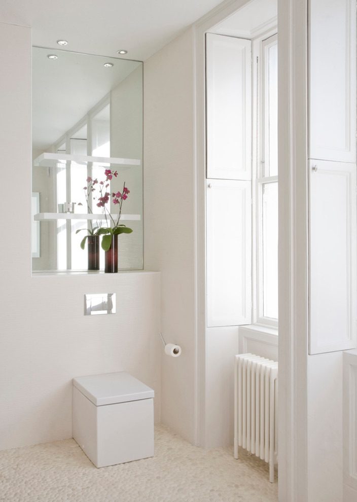 Cette image montre une grande salle de bain principale minimaliste avec une baignoire indépendante, WC à poser, un carrelage blanc, un mur blanc et un sol en galet.