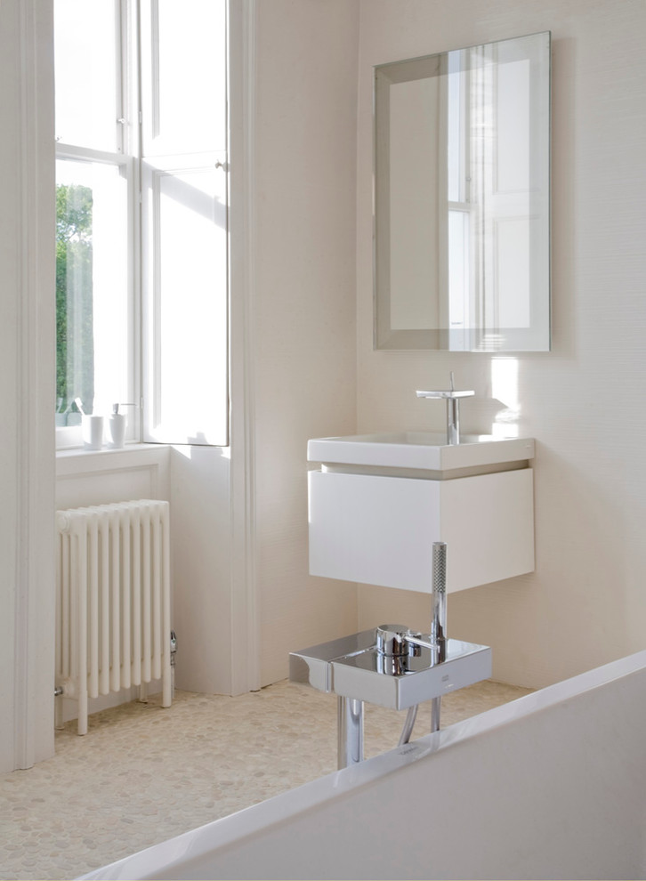 Modelo de cuarto de baño minimalista grande con lavabo suspendido, bañera exenta, baldosas y/o azulejos blancos, paredes blancas y suelo de baldosas tipo guijarro