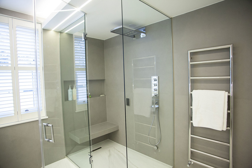 Example of a large trendy master white tile and marble tile marble floor doorless shower design in London with flat-panel cabinets, white cabinets, a one-piece toilet, white walls, a console sink and quartz countertops