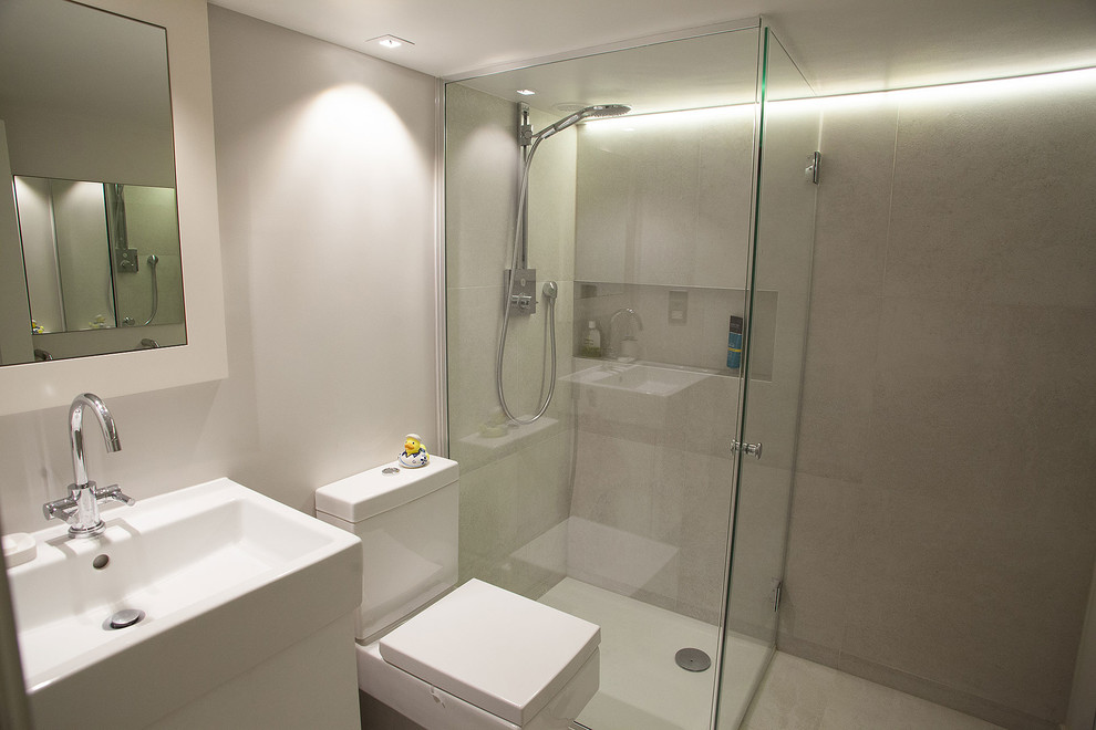 Example of a small trendy master beige tile and porcelain tile porcelain tile doorless shower design in London with flat-panel cabinets, white cabinets, a one-piece toilet, beige walls, a console sink and quartz countertops