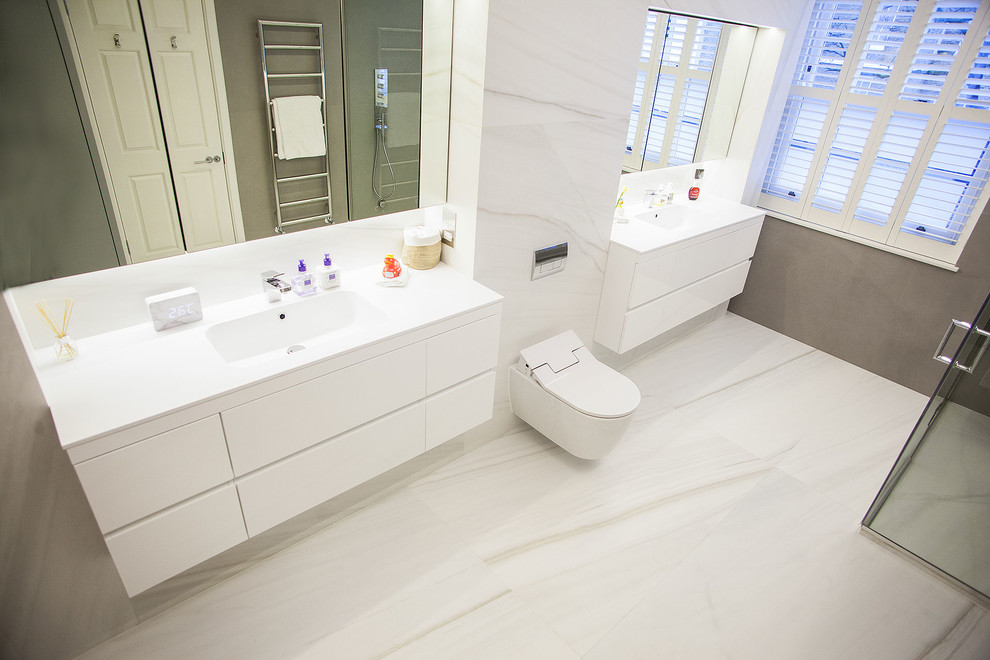 Design ideas for a large contemporary ensuite bathroom in London with flat-panel cabinets, white cabinets, a walk-in shower, a one-piece toilet, white tiles, marble tiles, white walls, marble flooring, a console sink and engineered stone worktops.