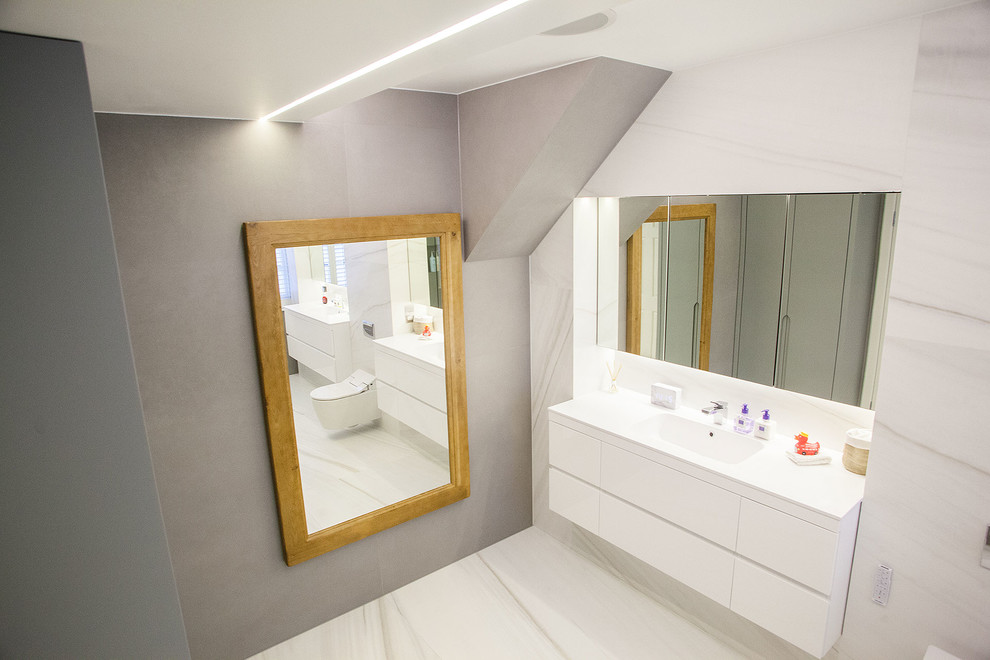 Inspiration for a large contemporary ensuite bathroom in London with flat-panel cabinets, white cabinets, a walk-in shower, a one-piece toilet, white tiles, marble tiles, white walls, marble flooring, a console sink and engineered stone worktops.