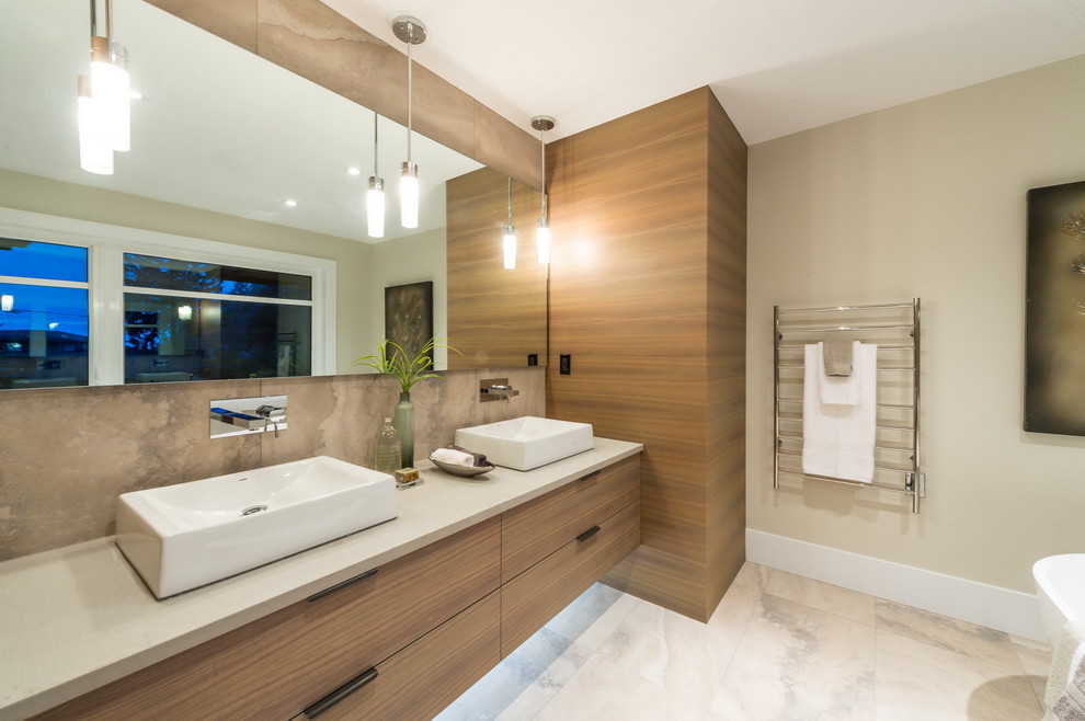 Modern inredning av ett stort en-suite badrum, med släta luckor, skåp i ljust trä, ett fristående badkar, beige kakel, stenkakel, marmorgolv, ett fristående handfat och bänkskiva i akrylsten