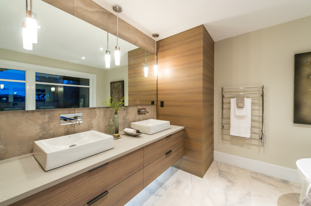 Inspiration for a large contemporary master beige tile and stone tile marble floor freestanding bathtub remodel in Vancouver with flat-panel cabinets, light wood cabinets, a vessel sink and solid surface countertops