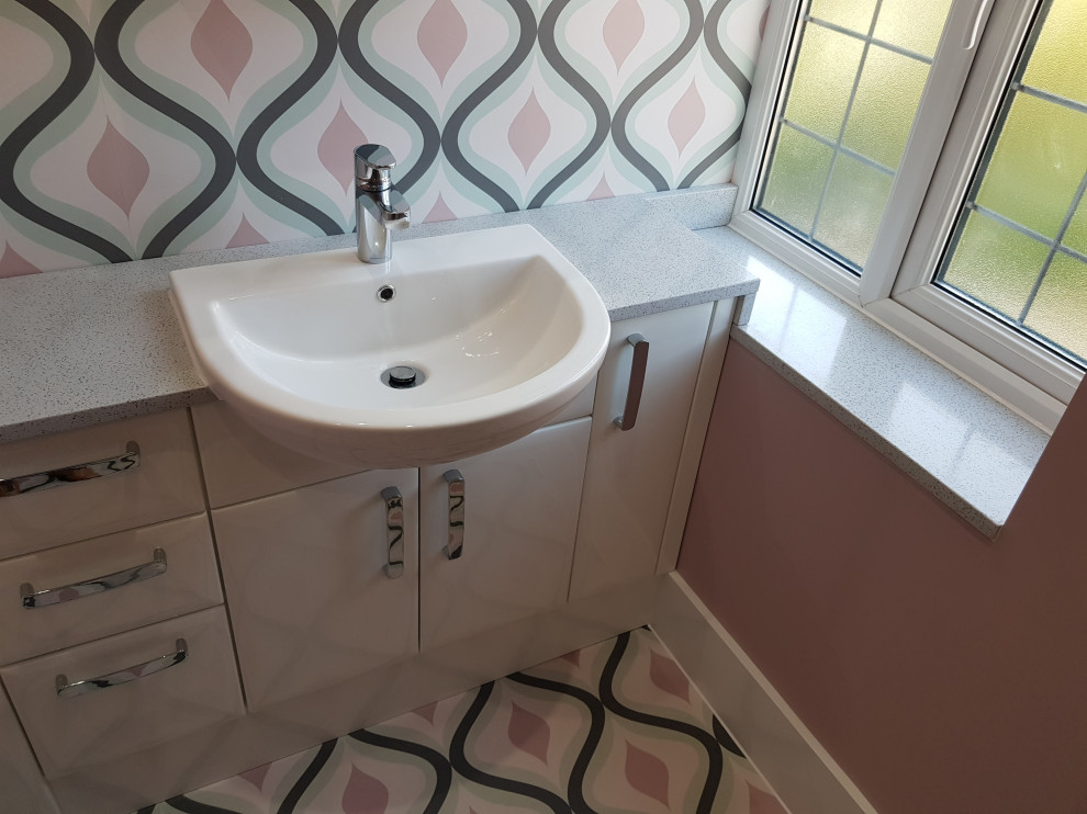 Exempel på ett stort modernt grå grått en-suite badrum, med släta luckor, vita skåp, en öppen dusch, en vägghängd toalettstol, vit kakel, keramikplattor, rosa väggar, vinylgolv, bänkskiva i akrylsten, flerfärgat golv och med dusch som är öppen