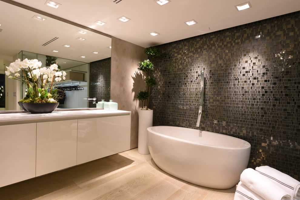 Esempio di una stanza da bagno padronale minimalista con ante lisce, ante bianche, vasca freestanding, piastrelle marroni, piastrelle a mosaico, parquet chiaro e top in quarzo composito