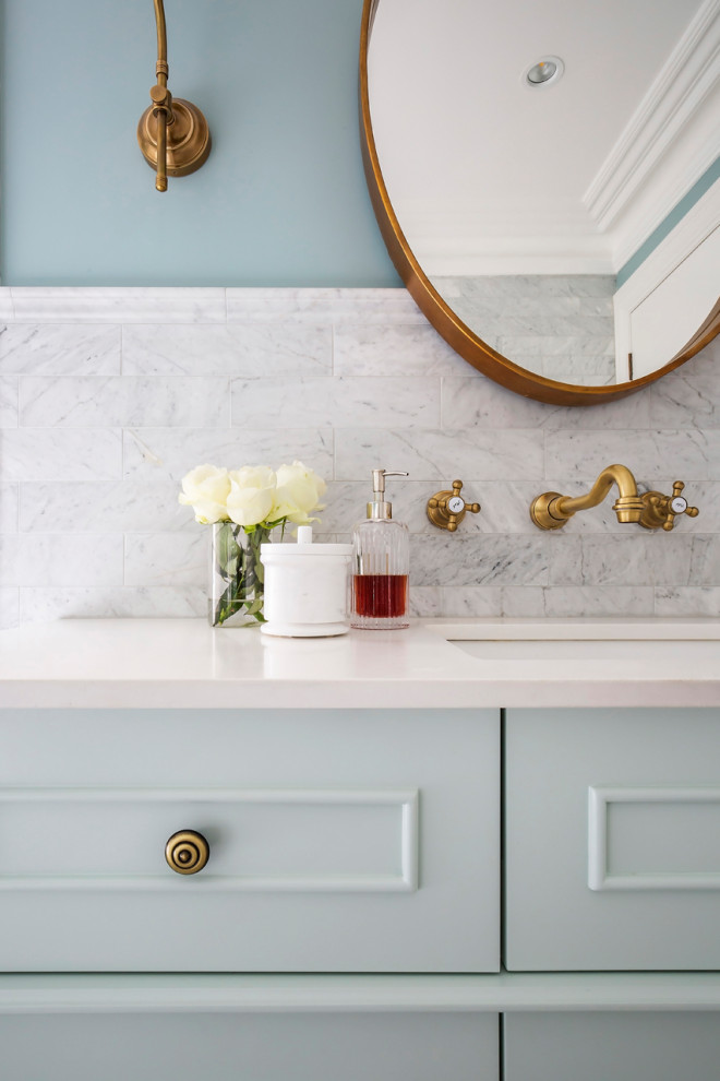 Cette image montre une salle de bain traditionnelle avec un placard à porte shaker, des portes de placards vertess, une baignoire posée, un carrelage gris, du carrelage en marbre, un sol en marbre, un lavabo encastré, un plan de toilette en marbre et un plan de toilette blanc.