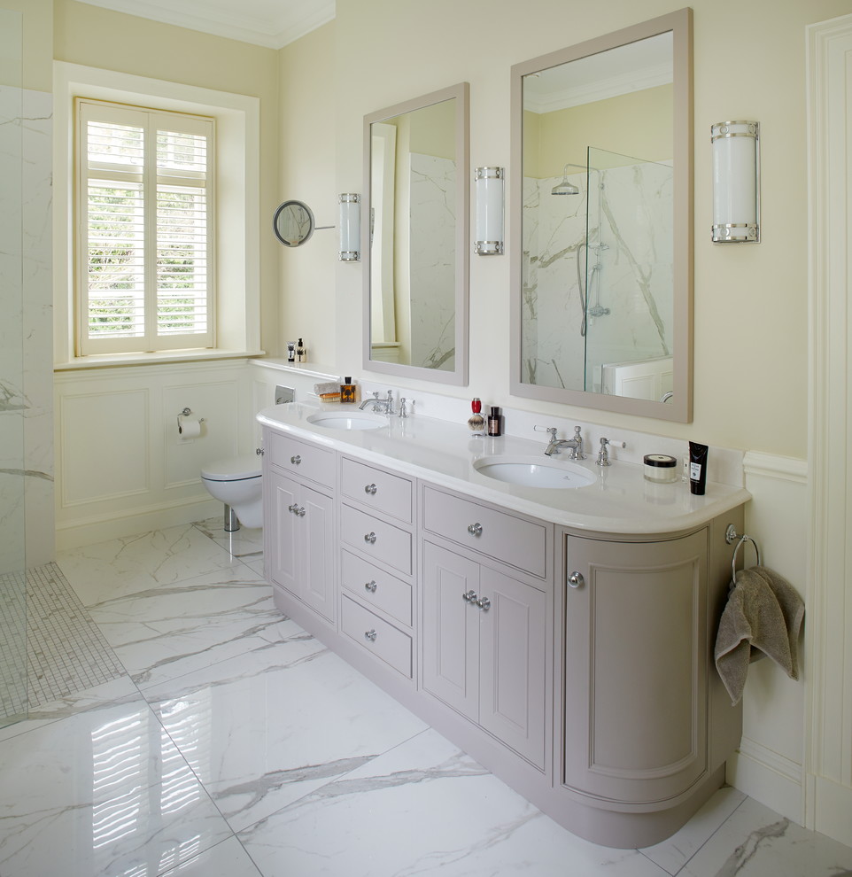 Idéer för att renovera ett stort vintage en-suite badrum, med luckor med infälld panel, grå skåp, ett fristående badkar, våtrum, en vägghängd toalettstol, vit kakel, porslinskakel, vita väggar, klinkergolv i porslin, ett undermonterad handfat och marmorbänkskiva