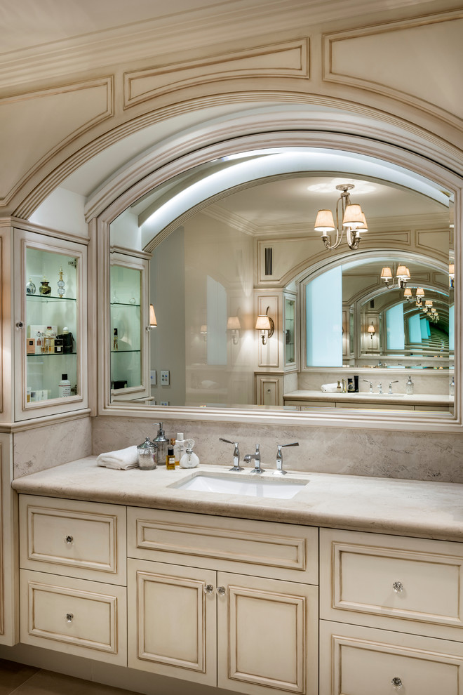 Idées déco pour une grande salle de bain principale classique en bois vieilli avec un placard avec porte à panneau encastré, un carrelage beige, un carrelage de pierre, un mur beige, un sol en marbre, un lavabo encastré et un plan de toilette en marbre.
