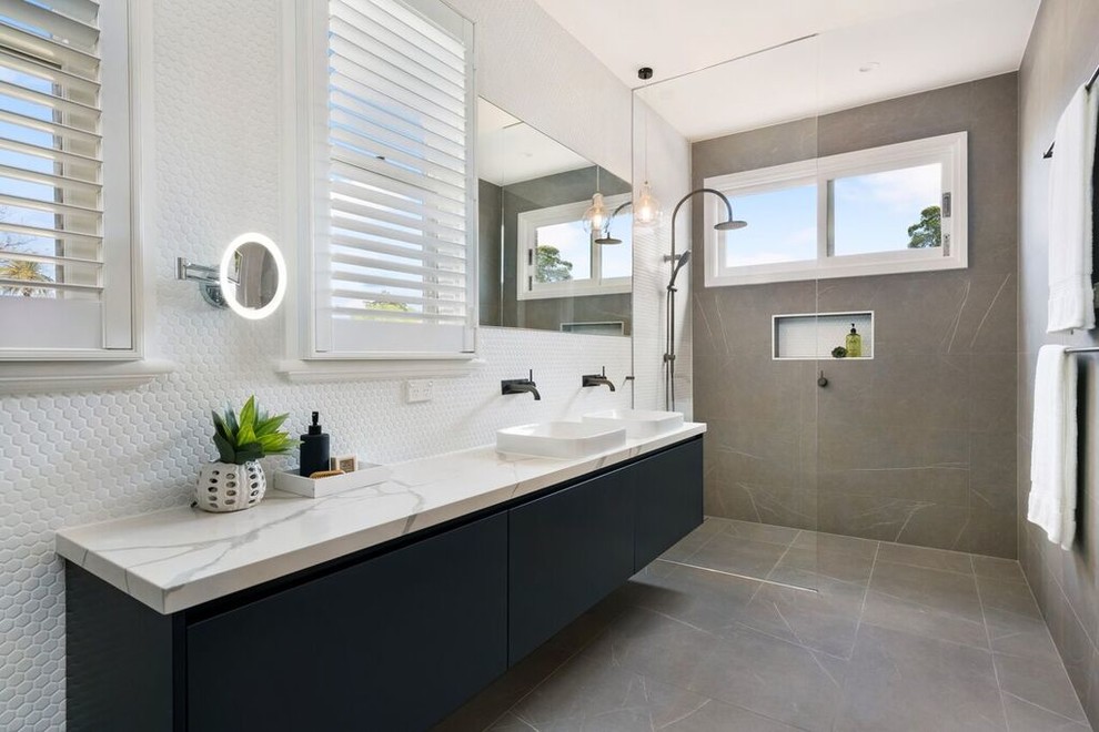 Modernes Duschbad mit flächenbündigen Schrankfronten, schwarzen Schränken, bodengleicher Dusche, weißen Fliesen, Mosaikfliesen, Aufsatzwaschbecken, grauem Boden, offener Dusche und weißer Waschtischplatte in Sydney