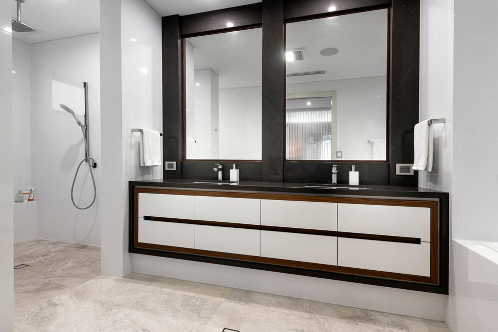 This is an example of a large contemporary ensuite bathroom in Perth with recessed-panel cabinets, white cabinets, a built-in bath, a walk-in shower, a one-piece toilet, white tiles, white walls, a submerged sink, engineered stone worktops, an open shower, brown worktops, limestone flooring and grey floors.