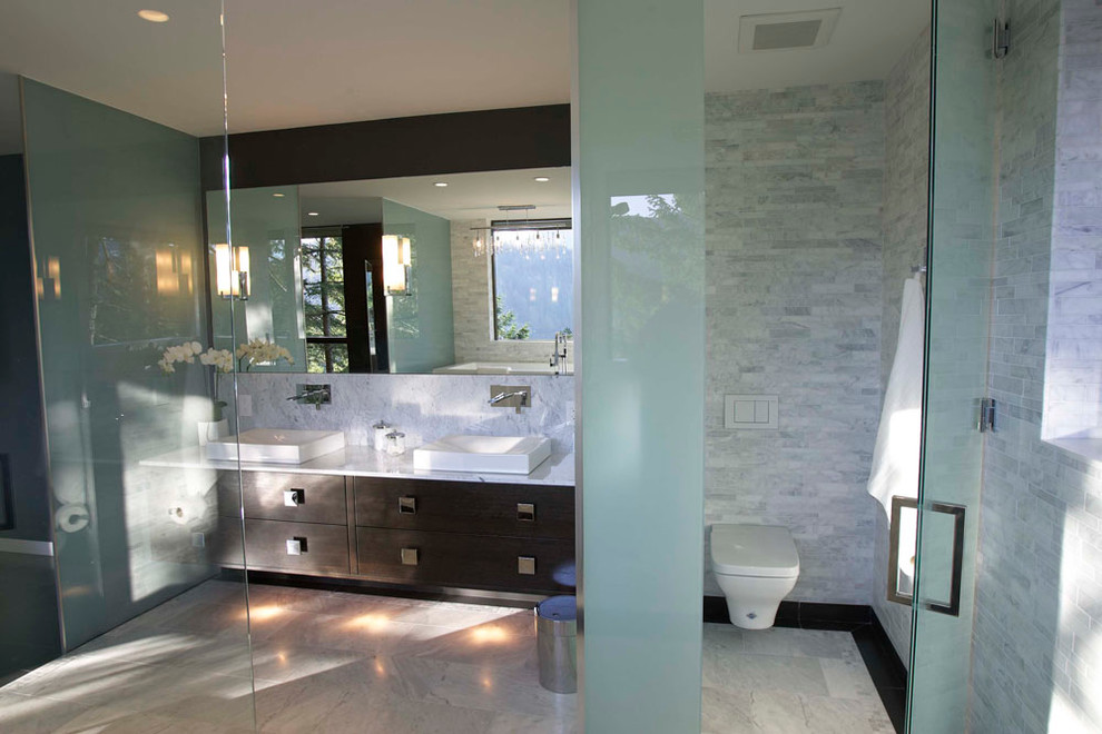 Bathroom - large contemporary gray tile and stone tile marble floor bathroom idea in Vancouver with a vessel sink, flat-panel cabinets, dark wood cabinets, marble countertops, a wall-mount toilet and gray walls
