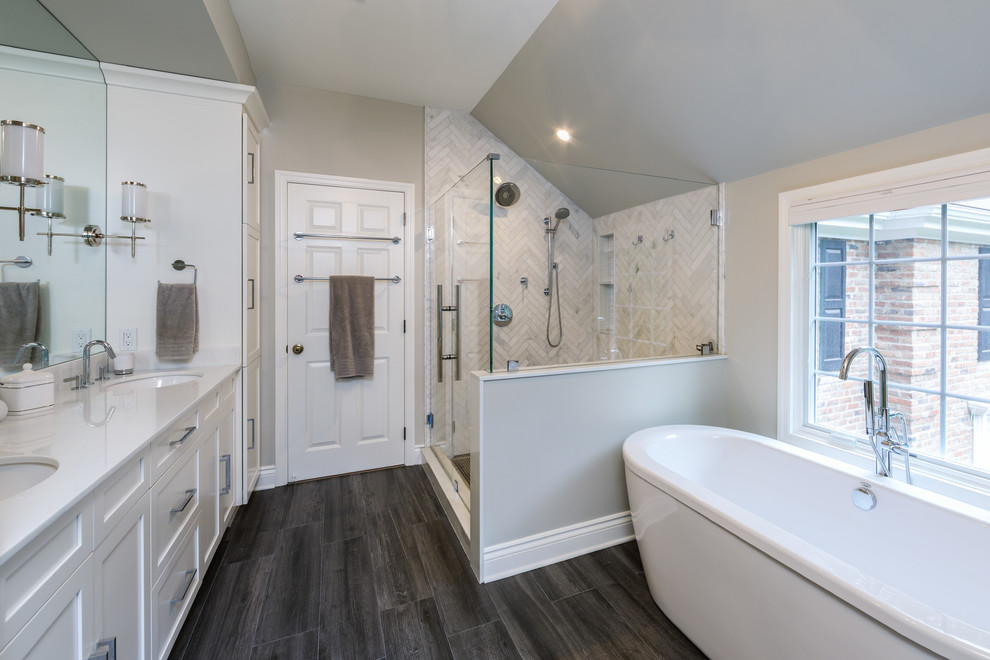 Inredning av ett klassiskt mellanstort vit vitt en-suite badrum, med skåp i shakerstil, vita skåp, ett fristående badkar, en hörndusch, grå kakel, marmorkakel, grå väggar, mörkt trägolv, ett undermonterad handfat, bänkskiva i kvarts, brunt golv och dusch med gångjärnsdörr