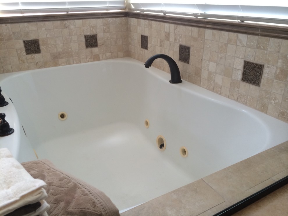 Exemple d'une salle de bain méditerranéenne avec une baignoire d'angle et un carrelage beige.