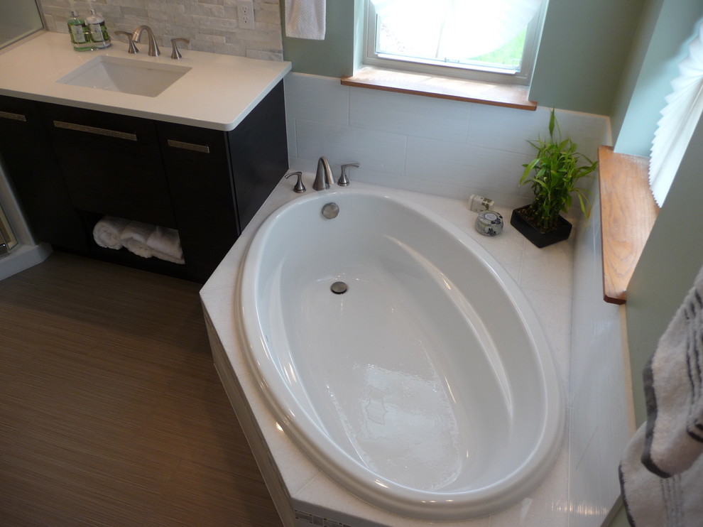 Aménagement d'une salle de bain contemporaine de taille moyenne avec une baignoire d'angle, un carrelage vert, des dalles de pierre, un mur vert, un lavabo encastré et un plan de toilette en quartz modifié.