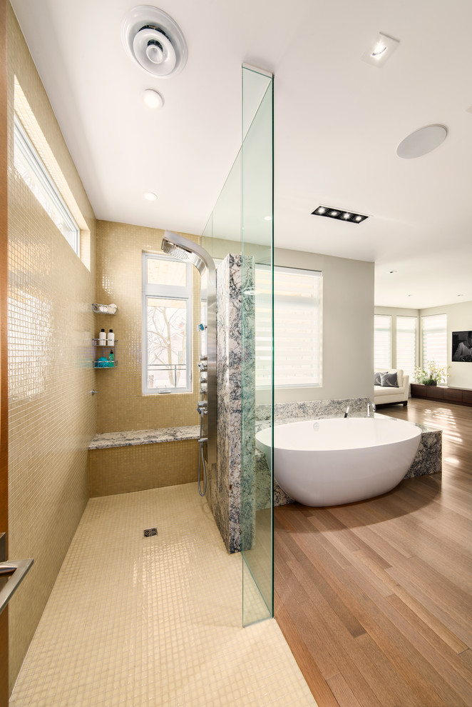 Cette image montre une salle de bain principale design avec une baignoire indépendante, une douche ouverte, un carrelage beige, un mur beige, un sol en bois brun et aucune cabine.