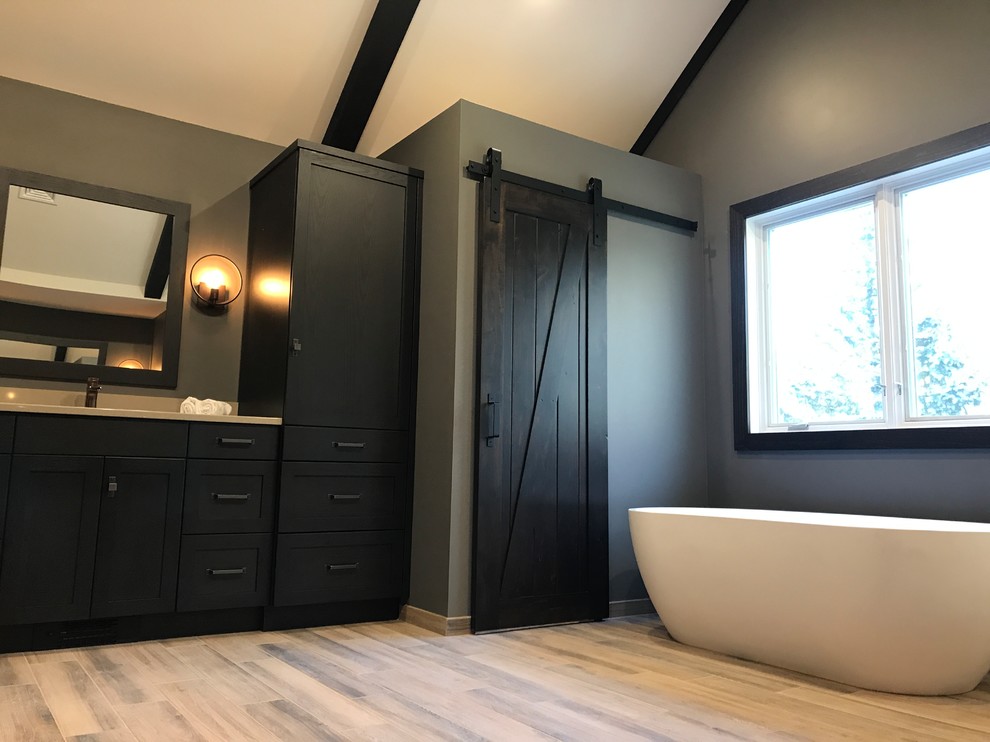 This is an example of a medium sized rustic ensuite bathroom in Philadelphia with dark wood cabinets, a freestanding bath, a one-piece toilet, light hardwood flooring, shaker cabinets, brown walls, a submerged sink, beige floors and solid surface worktops.