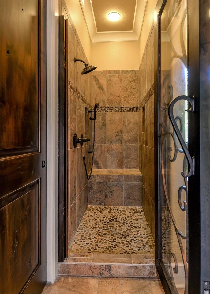 Idées déco pour une douche en alcôve principale méditerranéenne de taille moyenne avec une baignoire indépendante, un carrelage marron, une plaque de galets, un mur jaune, un sol en galet et un lavabo encastré.