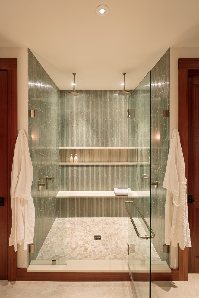 This is an example of a large world-inspired ensuite bathroom in Hawaii with shaker cabinets, medium wood cabinets, an alcove shower, a one-piece toilet, green tiles, glass tiles, white walls, porcelain flooring, a built-in sink, engineered stone worktops, beige floors and a hinged door.