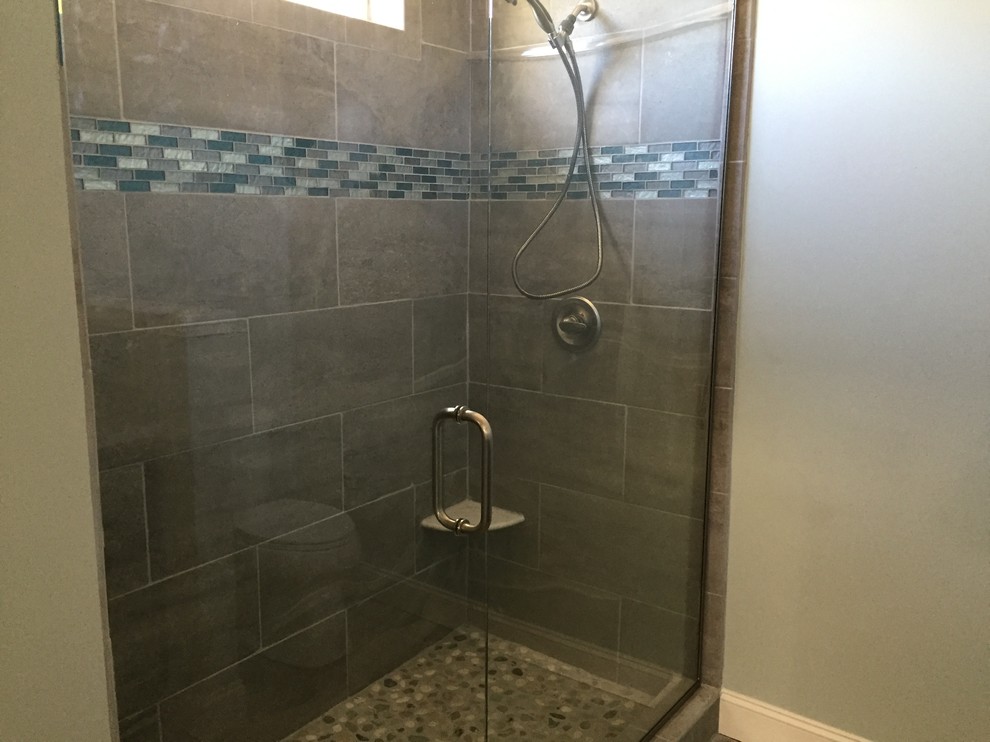 Amerikansk inredning av ett litet badrum med dusch, med luckor med upphöjd panel, skåp i mörkt trä, ett hörnbadkar, en öppen dusch, en toalettstol med hel cisternkåpa, grå kakel, vit kakel, mosaik, beige väggar, klinkergolv i småsten, ett nedsänkt handfat, granitbänkskiva, brunt golv och med dusch som är öppen