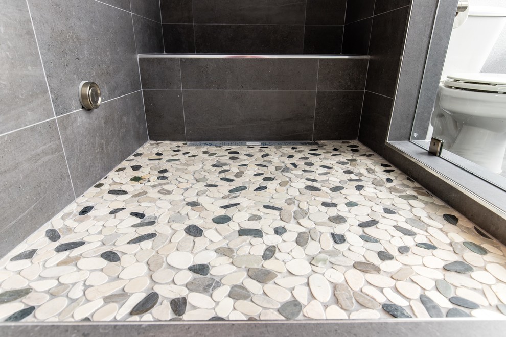 Exempel på ett mellanstort modernt en-suite badrum, med släta luckor, skåp i mörkt trä, en dusch/badkar-kombination, klinkergolv i småsten, bänkskiva i kvarts, flerfärgat golv och dusch med gångjärnsdörr