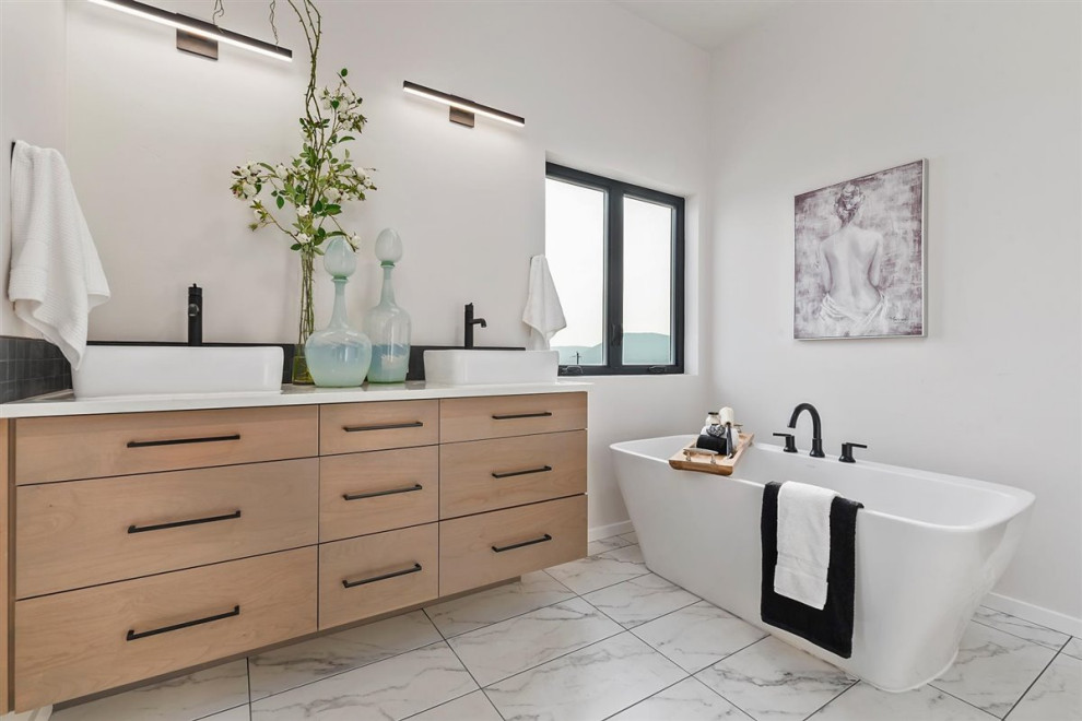 Bild på ett mellanstort funkis vit vitt en-suite badrum, med släta luckor, skåp i ljust trä, bänkskiva i kvartsit, ett fristående badkar, vita väggar, klinkergolv i porslin och vitt golv