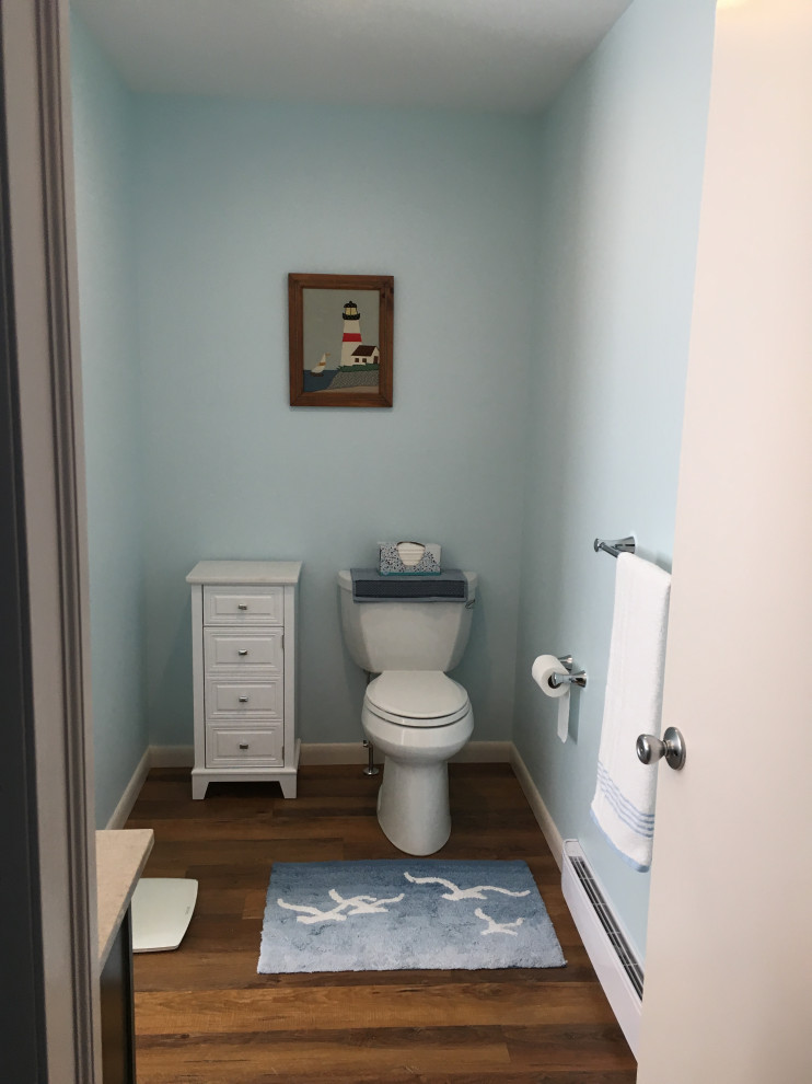 Mittelgroße Klassische Gästetoilette mit profilierten Schrankfronten, dunklen Holzschränken, Toilette mit Aufsatzspülkasten, blauer Wandfarbe, Vinylboden, integriertem Waschbecken, Mineralwerkstoff-Waschtisch, braunem Boden und beiger Waschtischplatte in Sonstige
